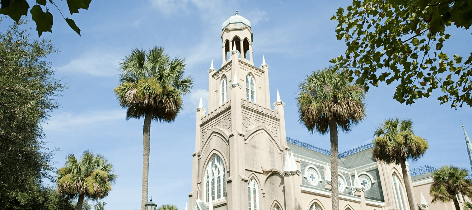 Historic building with palm trees and tower.