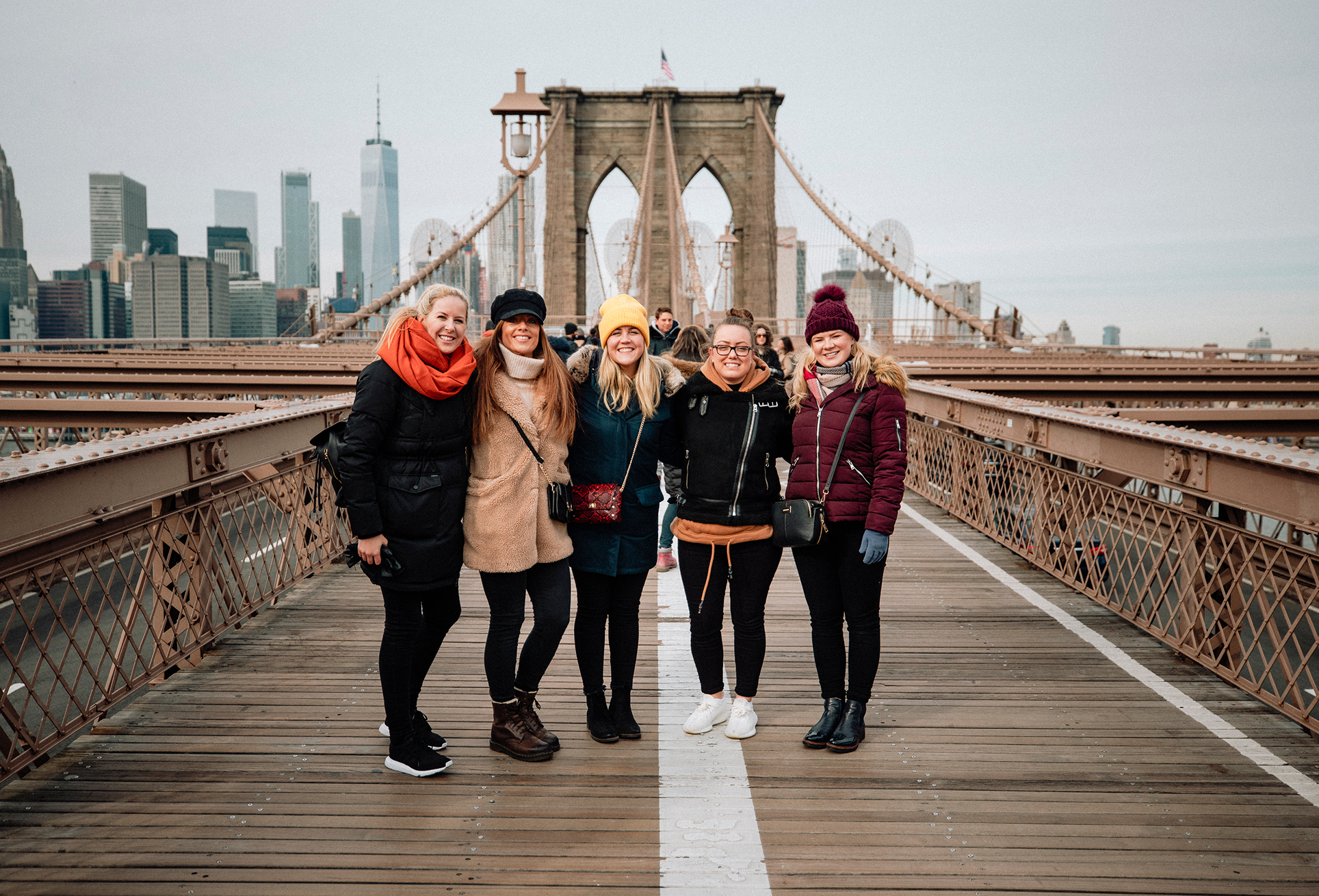 Group of women on Brooklyn Bridge walkway.