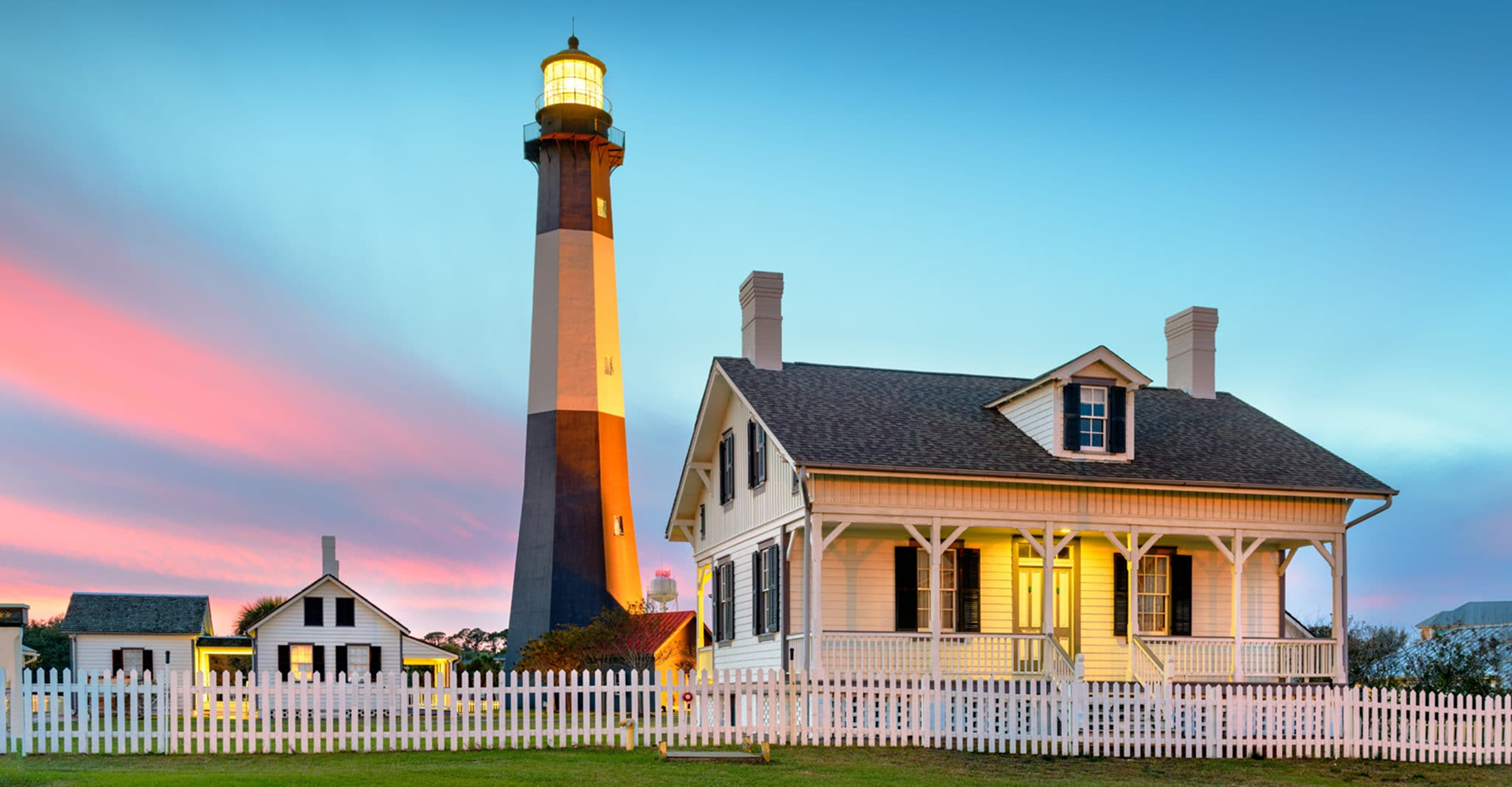 Lighthouse and house at sunset.